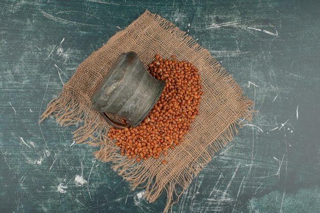 Ancient kettle with wheat on burlap on marble surface 