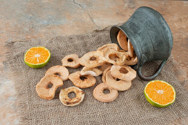 Ancient teapot full of dried apples with half cut tangerine