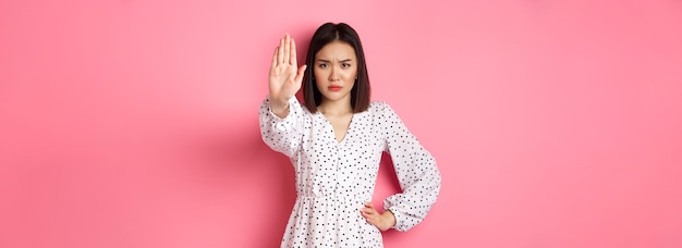 La donna asiatica arrabbiata dice di smettere di estendere il braccio per proibire o disapprovare qualcosa di accigliato stand scontento