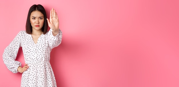 Foto gratuita la donna asiatica arrabbiata dice di smettere di estendere il braccio per proibire o disapprovare qualcosa di accigliato stand scontento