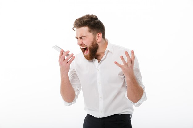 Angry bearded man in business clothes screaming at smartphone
