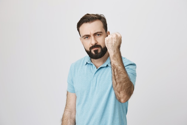 Angry bearded middle-aged father scolding, shaking fist in threaten