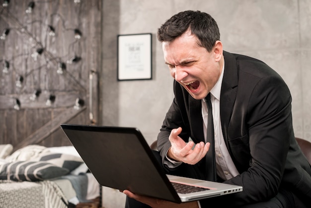Angry businessman yelling at laptop at home