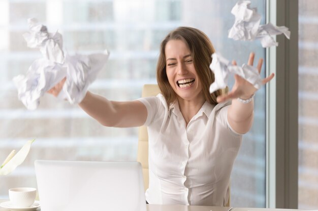 Angry businesswoman throwing crumbled papers
