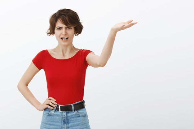 Angry and complaining woman arguing, pointing hand right with mad face