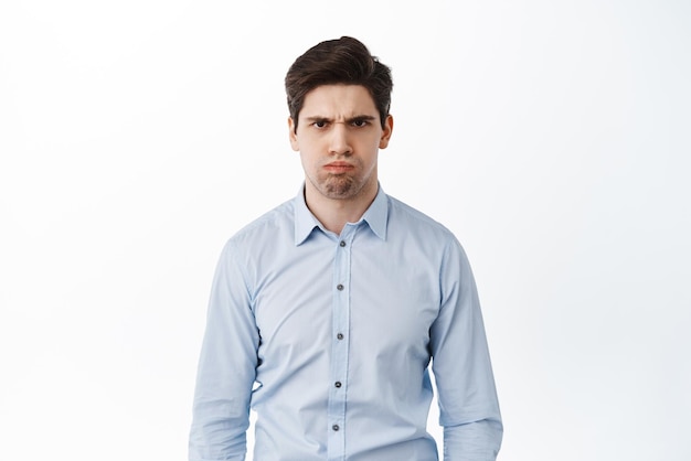 Angry and displeased office worker frowning and looking mad standing bothered or insulted losing temper boiling from anger standing over white background