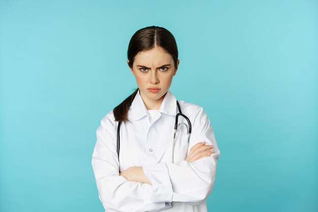 Angry doctor female medical worker looking offended cross arms on chest frowning and staring annoyed...