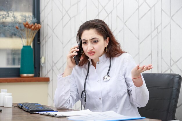 Angry doctor talking on the phone while sitting at the office High quality photo