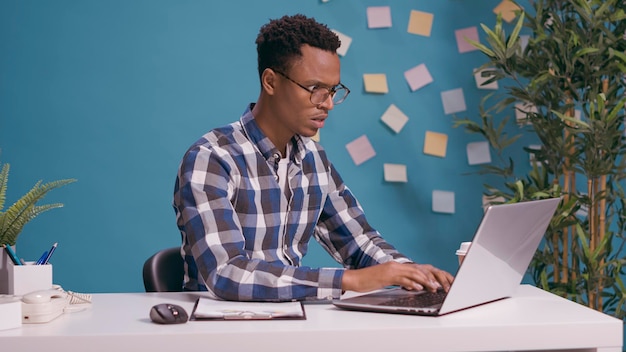 Angry employee having furious reaction about business work, feeling furious while he uses laptop computer on desk. Office worker feeling annoyed and tense about job problem, freelance failure.