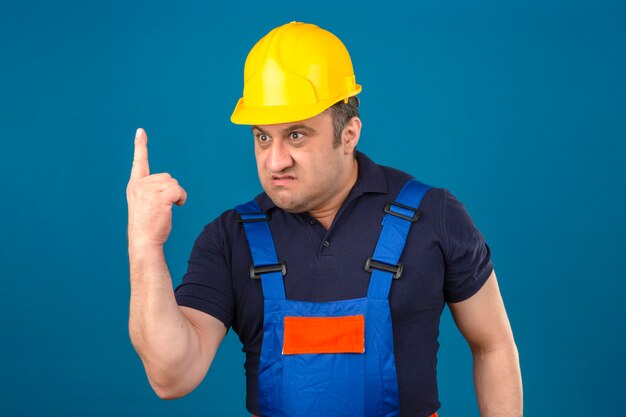 建設の制服と安全ヘルメットの人差し指を身に着けている猛烈な中年の男の怒り