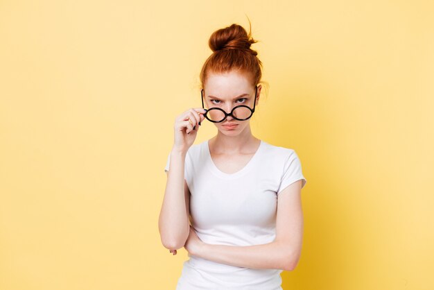 Angry ginger woman looking through eyeglasses