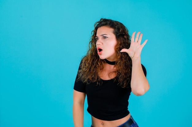 Angry girl is looking left by showing five gesture on blue background