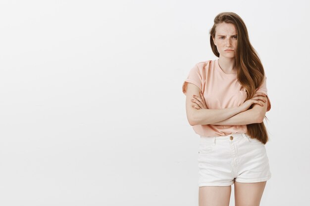 Angry and gloomy teenage girl posing against the white wall