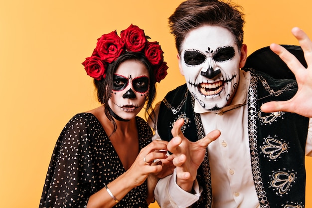 Злой парень с мексиканской страшной маской позирует. Пара стильных зомби дурачится на хэллоуин.