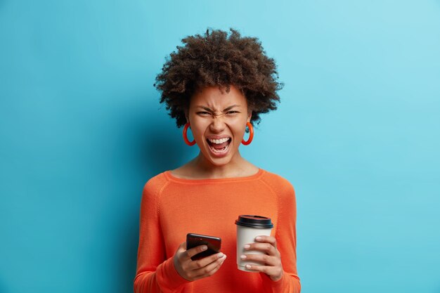 怒っているイライラした女性は携帯電話の叫び声を大声で笑う顔はコーヒーを飲みに行く