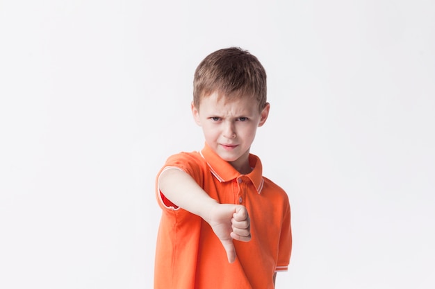 Angry little boy showing dislike gesture on white backdrop