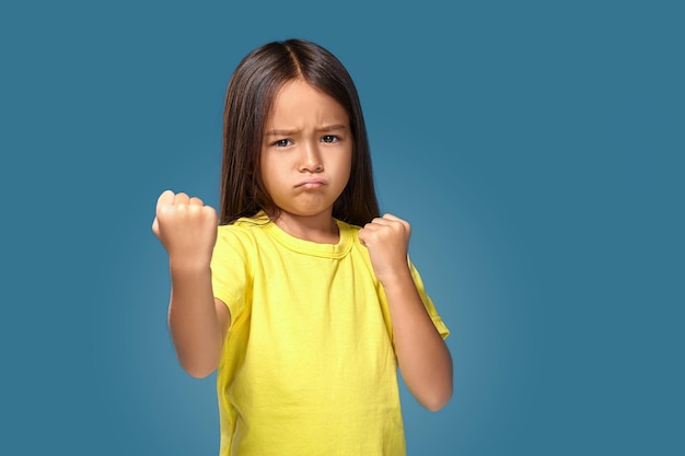 Angry little kid showing frustration and disagreement on blue background