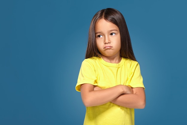 Angry little kid showing frustration and disagreement on blue background