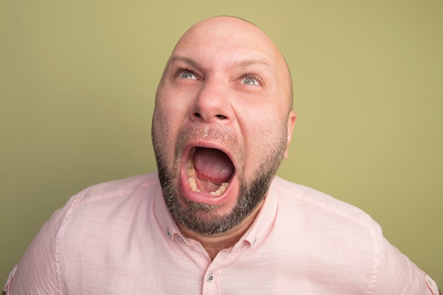 Free photo angry looking up middle-aged bald man wearing pink t-shirt