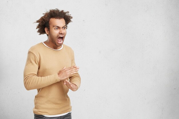 Angry man man shows stop gesture, crosses hands, asks not to bother him