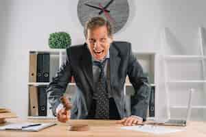 Free photo an angry mature lawyer hitting mallet on sounding block in the courtroom