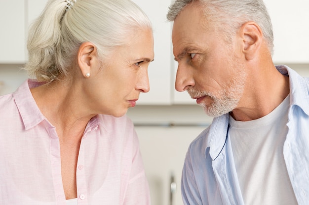 Angry mature man standing near mature serious woman