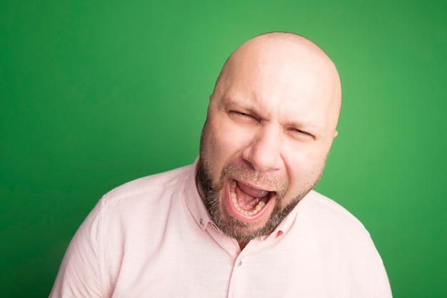 Angry middle-aged bald man wearing pink t-shirt