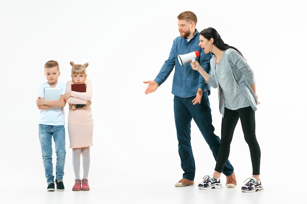 Angry parents scolding their children - son and daughter at home. Studio shot of emotional family. Human emotions, childhood, problems, conflict, domestic life, relationship concept