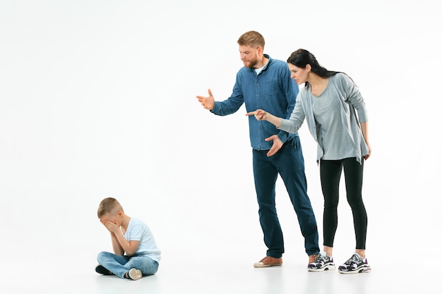 Angry parents scolding their son at home. Studio shot of emotional family. Human emotions, childhood, problems, conflict, domestic life, relationship concept