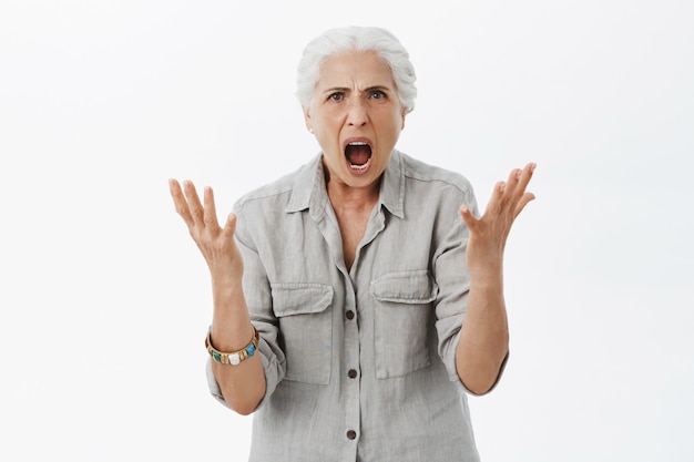 Angry pissed-off old granny shaking hands and shouting, being mad at person