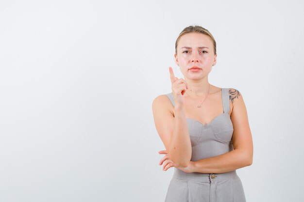 怒っているきれいなブロンドの女性は指を上げて、白い背景で孤立して怒った