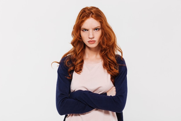 Free photo angry pretty young redhead lady with arms crossed.