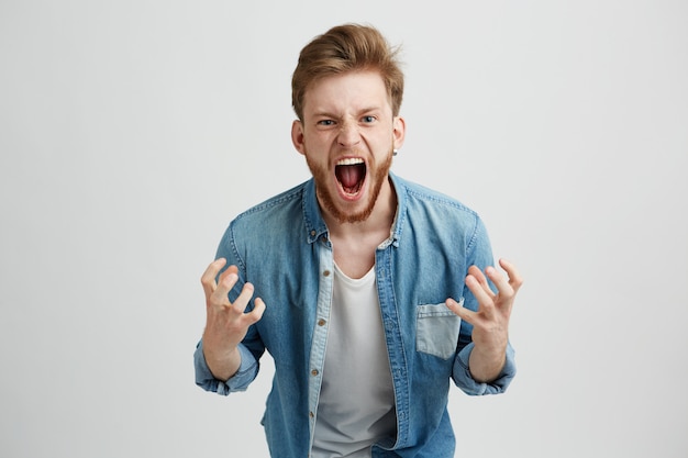 Бесплатное фото Злой гнев молодой человек с бородой кричать, кричать, жесты.