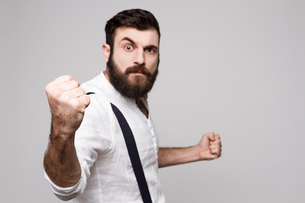 Angry rude young handsome man showing fist over white.