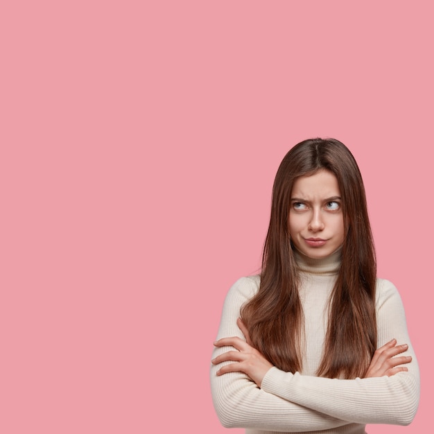 Free photo angry sad young lady crossed hands over chest, has offensive facial expression, looks through eyebrows