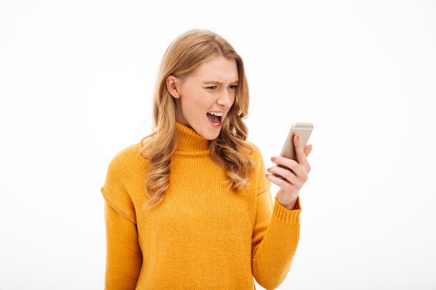 Angry screaming young woman using mobile phone.