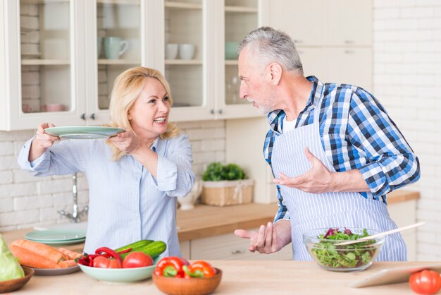 An angry senior couple fighting with each other in the kitchen