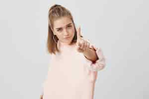 Free photo angry serious girl looking with appeal , holding her index finger in front, saying: hey, wait a minute. confident young european female defending her position and views. body language.