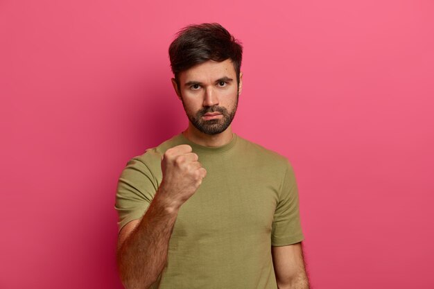 Angry strict man with thick beard, being furious, expresses warning and threat