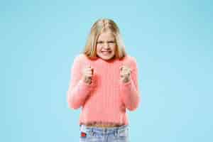 Free photo angry teen girl standing on trendy blue studio.