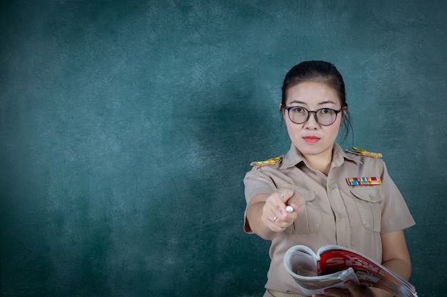 Free photo angry thai teacher in official outfit  standing in front of backboard pointing finger to camera