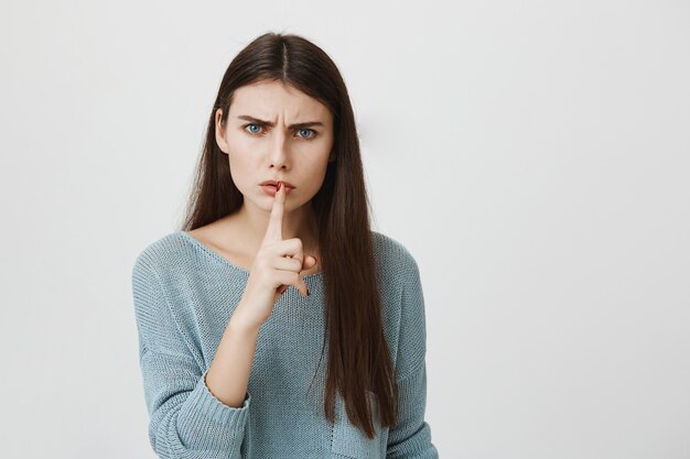 Angry woman frowning, shush to keep quiet