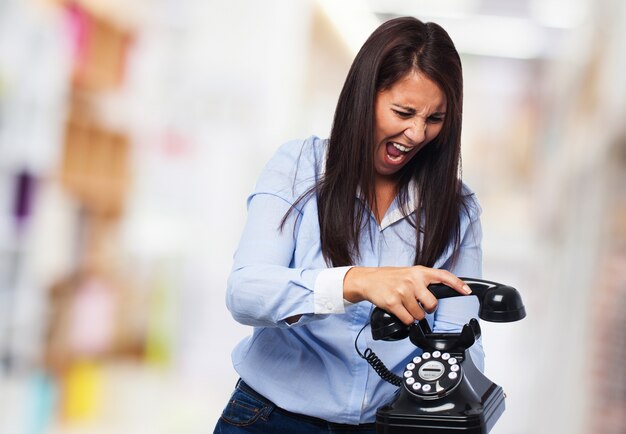 Angry woman hanging a phone while screaming