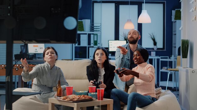 Angry woman losing video games on tv console after work, playing with colleagues on free time. Workmates using joysticks and television to do fun activity and entertainment at office