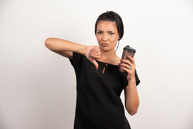 Angry woman making thumbs down because of taste of coffee.