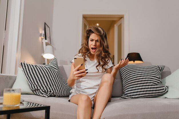 Angry woman in shorts and white t-shirt reading phone message