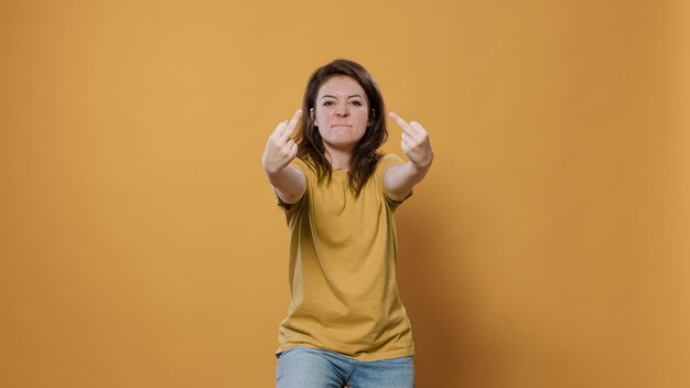 Злая женщина, показывающая непристойный жест рукой средним пальцем, имеет проблему с агрессивным отношением, будучи грубой и неуважительной в студии. Несчастный человек, имеющий конфликт, проявляющий агрессию и гнев.