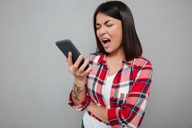 Angry young asian woman isolated using phone.