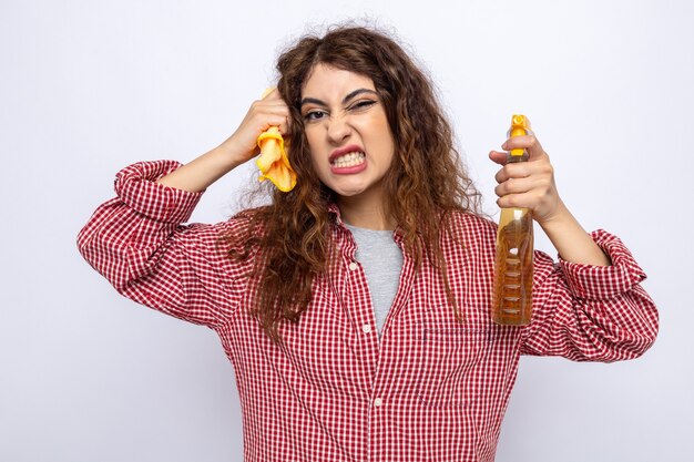 Free photo angry young cleaning woman holding cleaning agent with rag