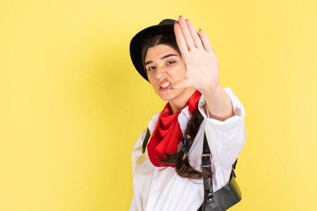 Angry young cowgirl raised her hand stand on yellow background High quality photo